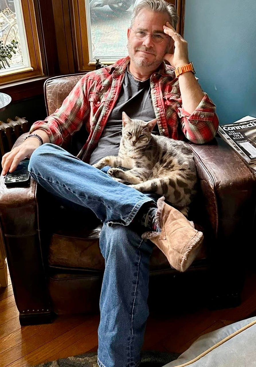 A relaxed owner reclining in his armchair with his Bengal stretched across his lap