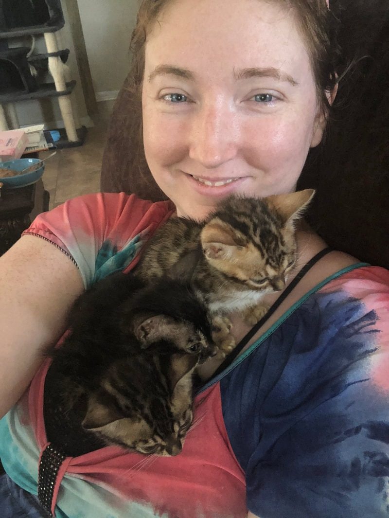 A smiling young woman holding her soft brown Bengal close