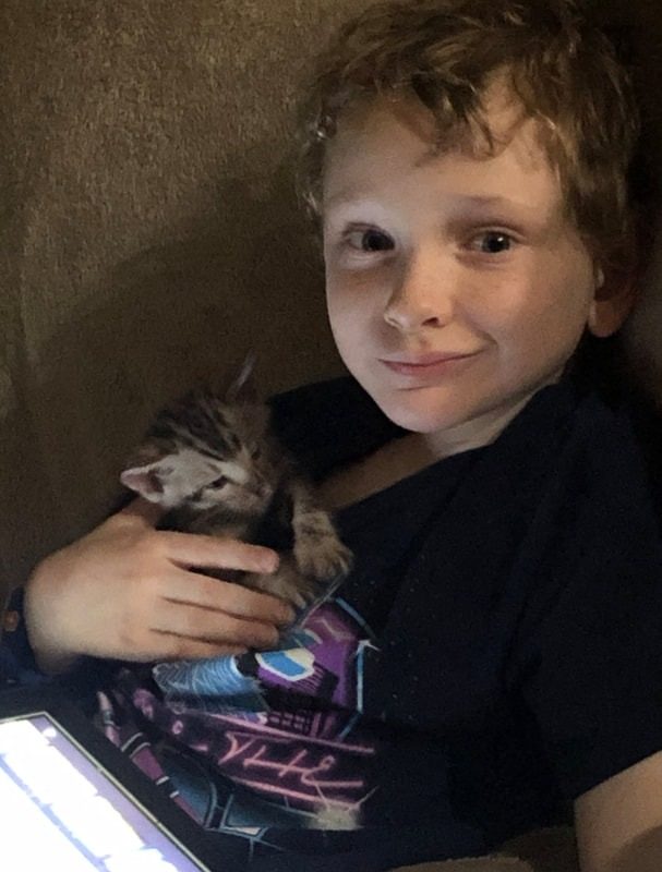 A boy cradling his Bengal kitten at home