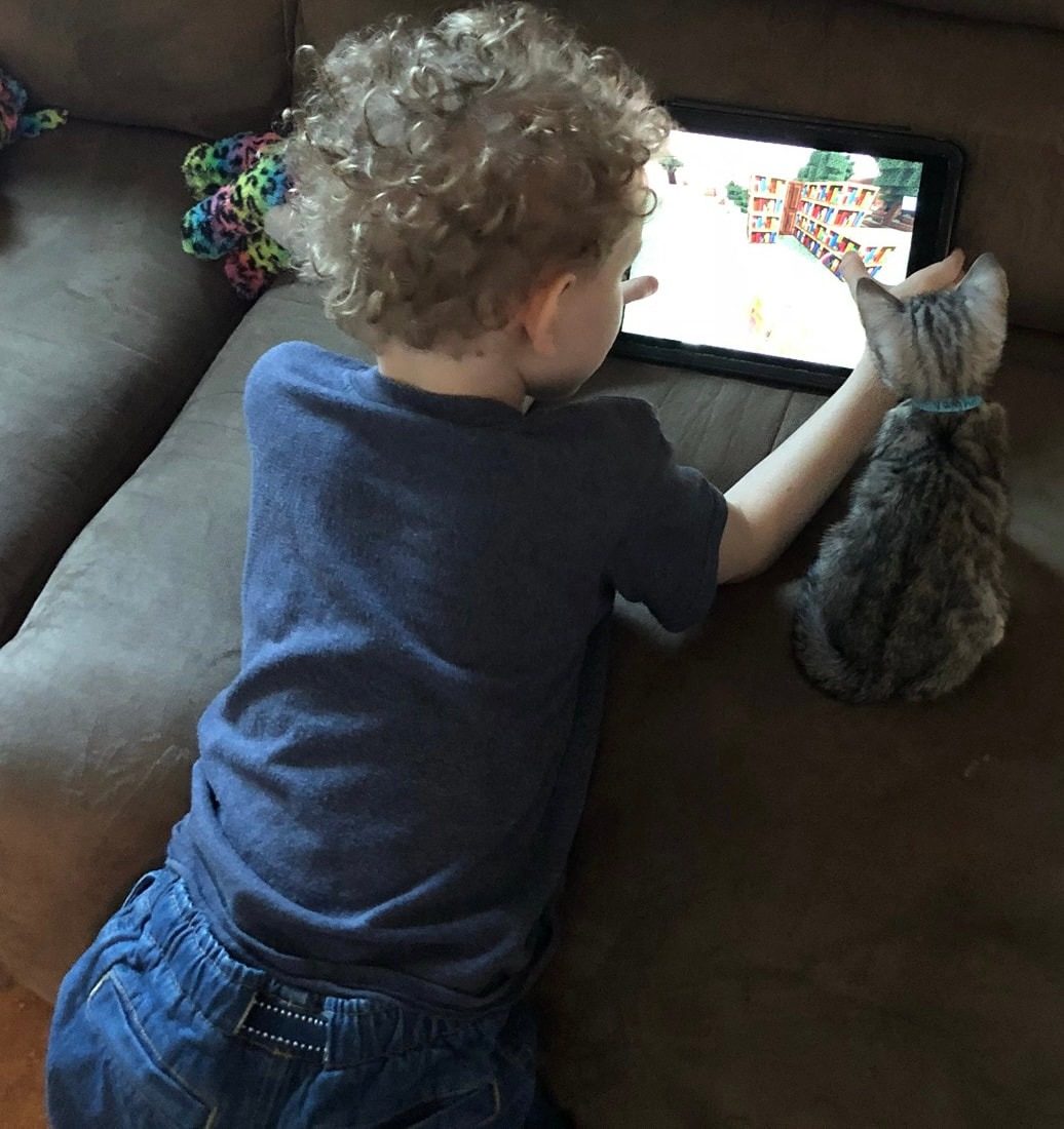 A young child sitting on the floor at home beside the family Bengal